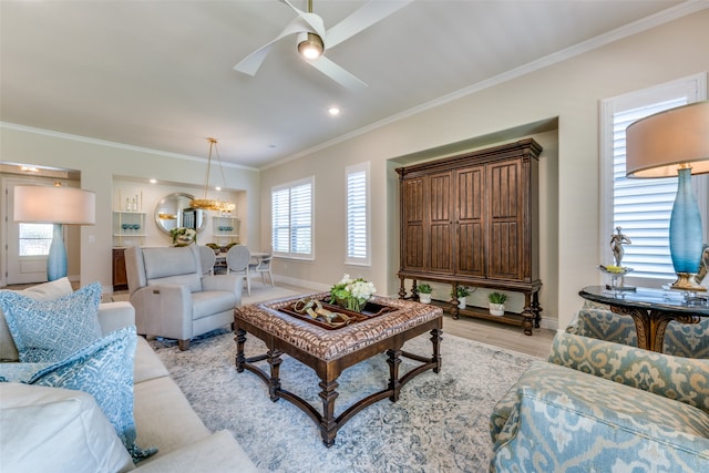 living room featuring ornamental molding, ceiling fan with notable chandelier, and light wood-type flooring