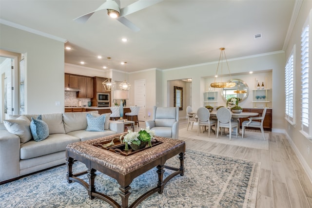 living room featuring ornamental molding, light wood-type flooring, and ceiling fan