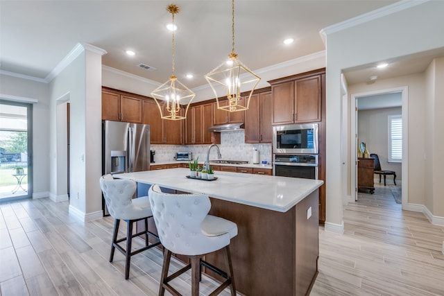 kitchen featuring light wood-type flooring, a center island, stainless steel appliances, pendant lighting, and a breakfast bar