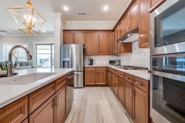 kitchen with appliances with stainless steel finishes, sink, hanging light fixtures, crown molding, and a chandelier