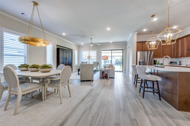 dining room with light hardwood / wood-style floors, crown molding, and ceiling fan with notable chandelier