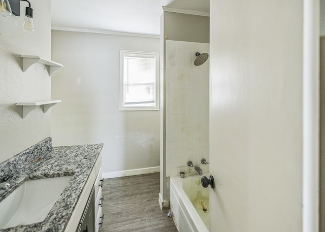 bathroom featuring ornamental molding, hardwood / wood-style flooring, tiled shower / bath combo, and vanity