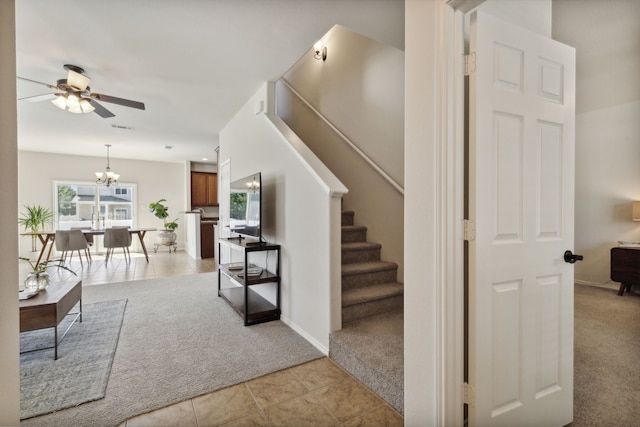 staircase with carpet floors and ceiling fan with notable chandelier