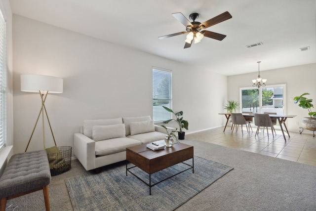 tiled living room with ceiling fan with notable chandelier