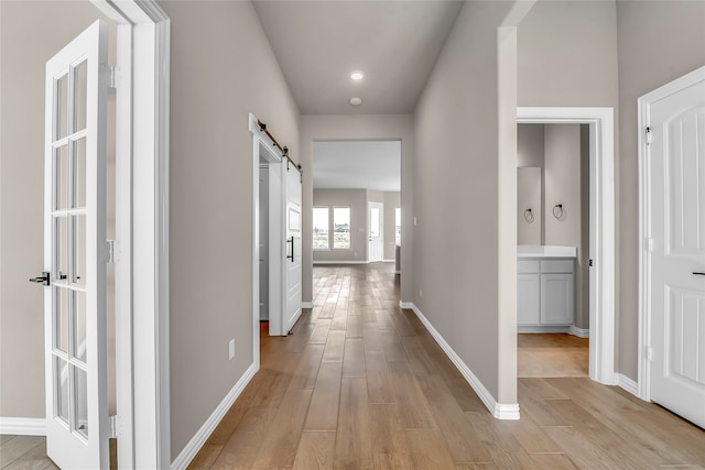 hall with a barn door and light wood-type flooring