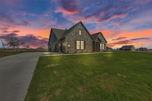 property exterior at dusk featuring a garage and a yard