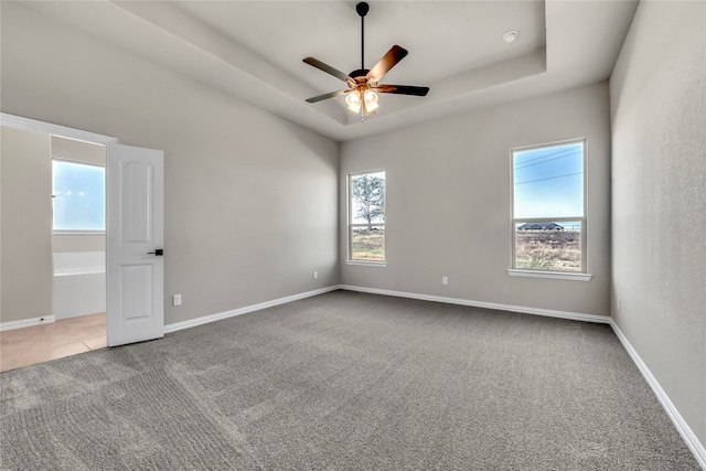 carpeted empty room featuring a raised ceiling and ceiling fan