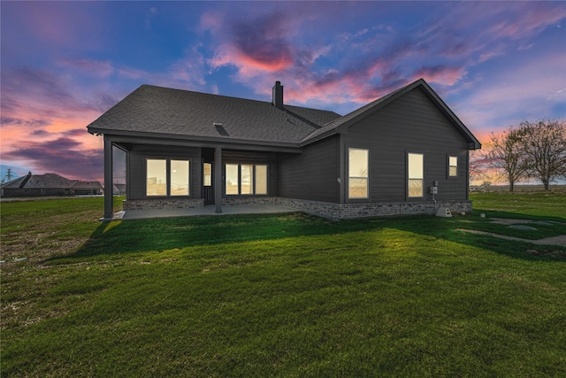 back house at dusk with a lawn