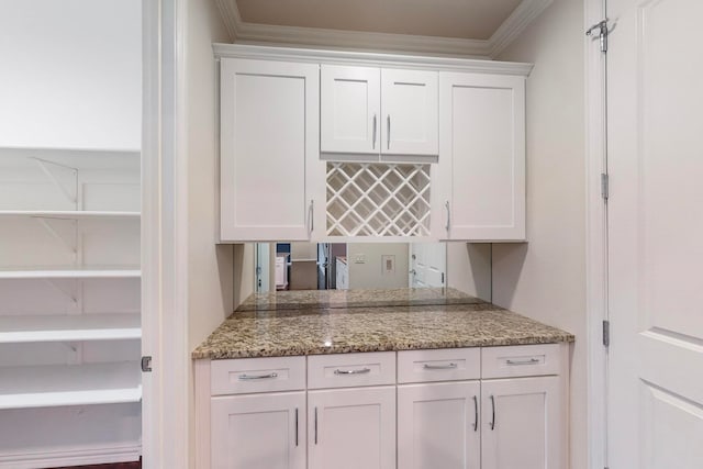 kitchen with light stone countertops, white cabinets, backsplash, and crown molding