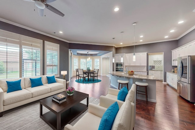 living room featuring crown molding, hardwood / wood-style floors, ceiling fan, and sink