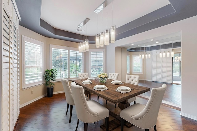 dining space with a notable chandelier, a raised ceiling, and dark hardwood / wood-style floors