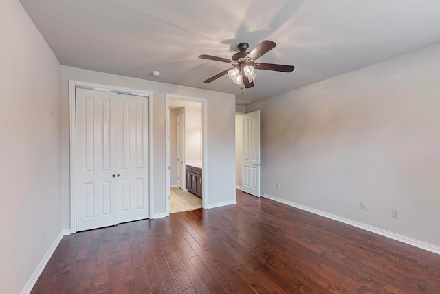 unfurnished bedroom featuring dark hardwood / wood-style flooring, ceiling fan, ensuite bath, and a closet