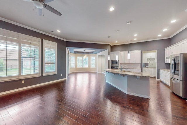 kitchen featuring hanging light fixtures, a center island with sink, white cabinetry, and stainless steel appliances