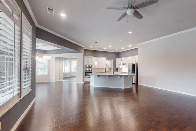 unfurnished living room featuring ceiling fan with notable chandelier, dark hardwood / wood-style floors, and ornamental molding