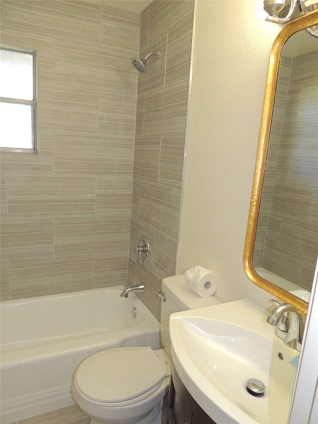 full bathroom featuring tiled shower / bath combo, vanity, and toilet