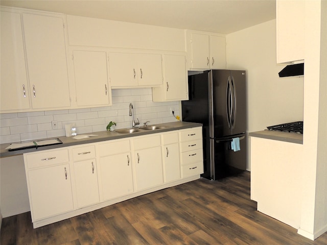 kitchen with dark wood-type flooring, sink, white cabinetry, stainless steel refrigerator, and backsplash