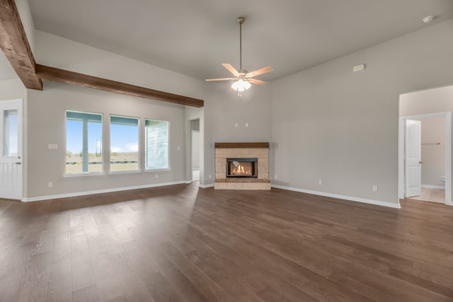 unfurnished living room featuring dark hardwood / wood-style floors, beam ceiling, and ceiling fan