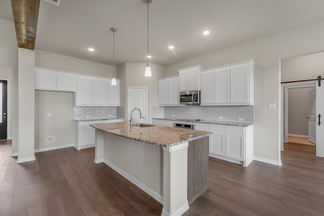 kitchen featuring a barn door, white cabinetry, stainless steel appliances, and dark hardwood / wood-style flooring