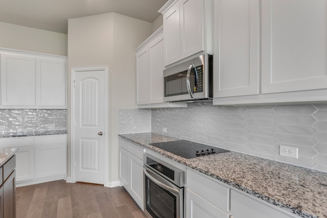 kitchen with stainless steel appliances, light hardwood / wood-style floors, tasteful backsplash, and white cabinetry