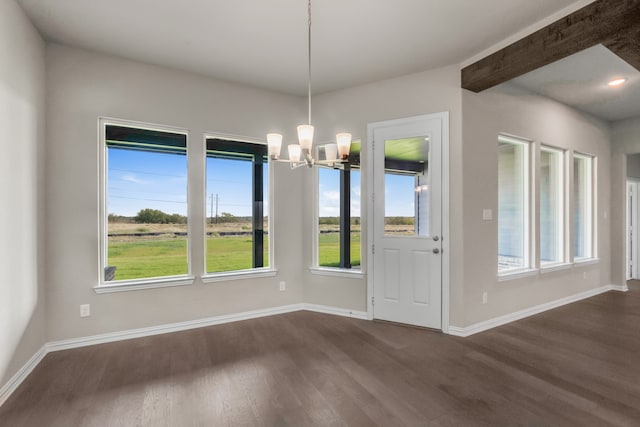 unfurnished dining area featuring dark wood-type flooring, a notable chandelier, and a wealth of natural light