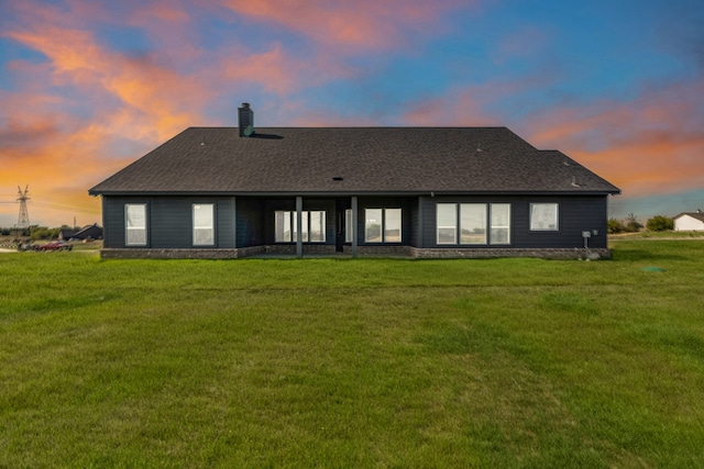 back house at dusk featuring a yard