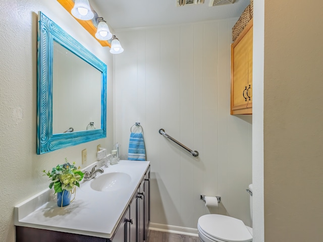 bathroom with vanity, wood walls, toilet, and hardwood / wood-style flooring