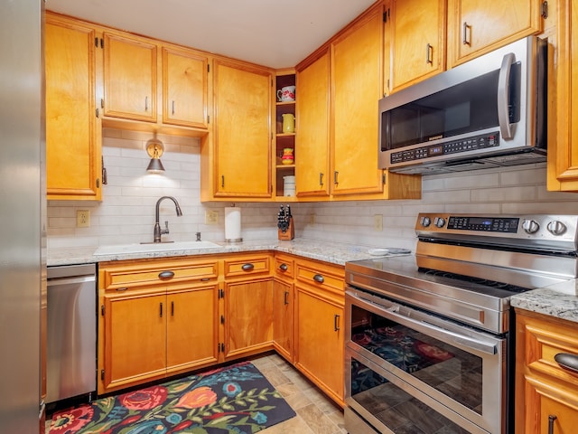 kitchen featuring appliances with stainless steel finishes, light stone countertops, sink, and tasteful backsplash