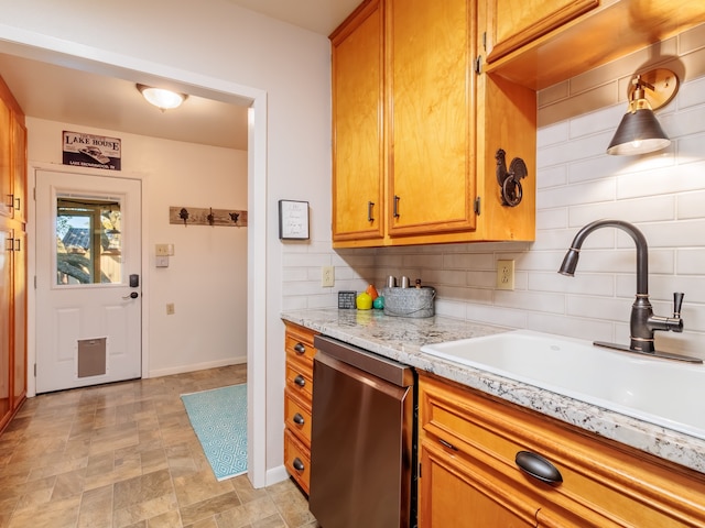 kitchen featuring light stone counters, dishwasher, sink, and decorative backsplash