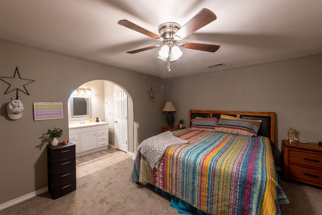 bedroom featuring ensuite bath, ceiling fan, and light colored carpet