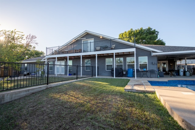 back of property with a fenced in pool, a yard, and a patio