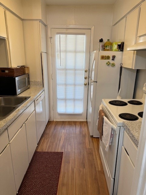 kitchen featuring light stone counters, hardwood / wood-style flooring, white appliances, and white cabinetry