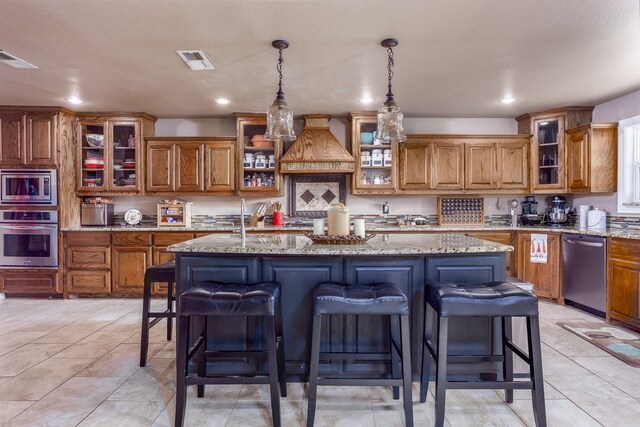 5903 Crowley Rd, Edgecliff Village, TX 76134 - kitchen with stainless steel appliances, brown cabinetry, a kitchen bar, custom exhaust hood, and a kitchen island with sink