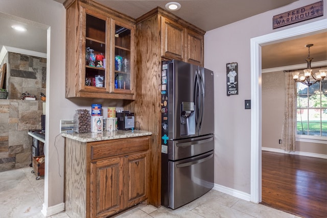 kitchen featuring light stone countertops, light wood-type flooring, crown molding, stainless steel refrigerator with ice dispenser, and a chandelier