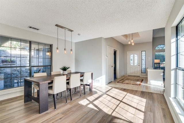 dining room featuring a textured ceiling, light hardwood / wood-style flooring, and a wealth of natural light