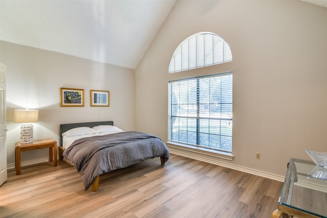 bedroom with light hardwood / wood-style flooring and high vaulted ceiling