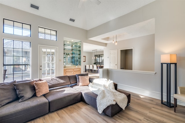 living room featuring a textured ceiling, ceiling fan, and light hardwood / wood-style flooring