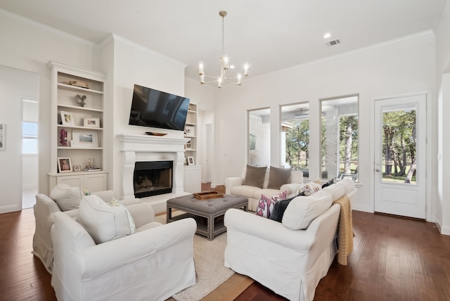 living room featuring built in shelves, a chandelier, dark wood-type flooring, and crown molding