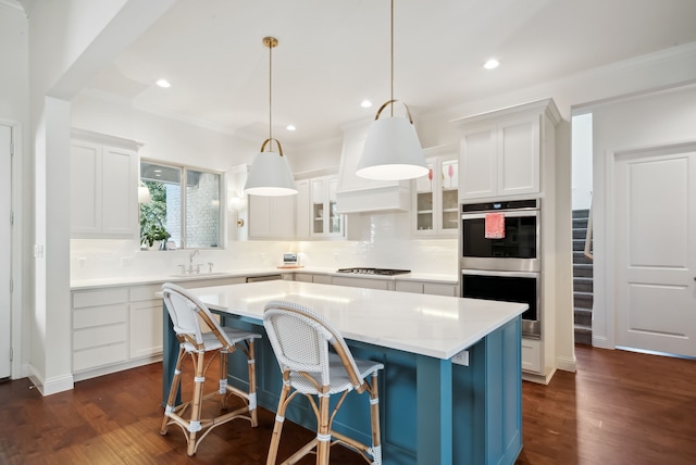 kitchen with pendant lighting, white cabinets, a kitchen island, dark hardwood / wood-style floors, and stainless steel double oven