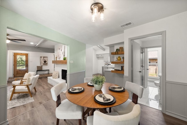 dining area with a fireplace, ceiling fan, and light hardwood / wood-style flooring