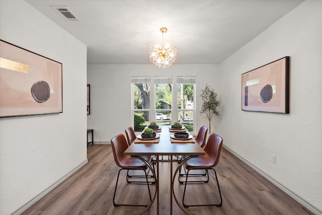 dining area with hardwood / wood-style flooring and a notable chandelier