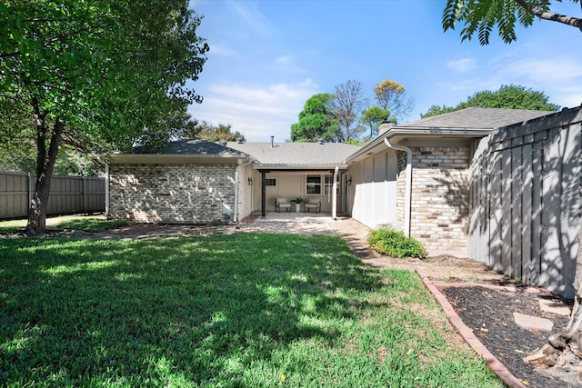 rear view of property featuring a lawn and a patio