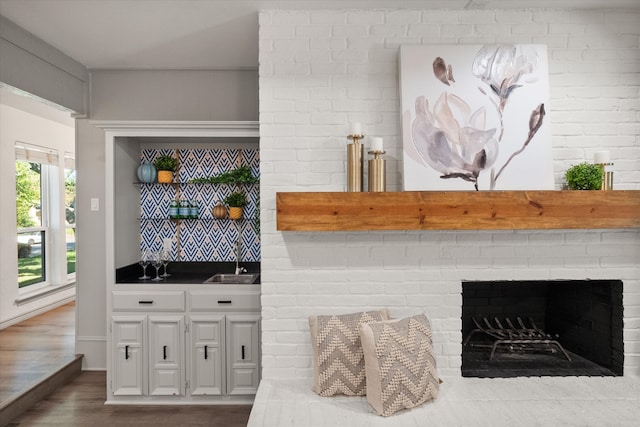 bar with a fireplace, dark wood-type flooring, and sink