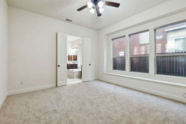 unfurnished bedroom featuring light carpet, ensuite bath, and ceiling fan