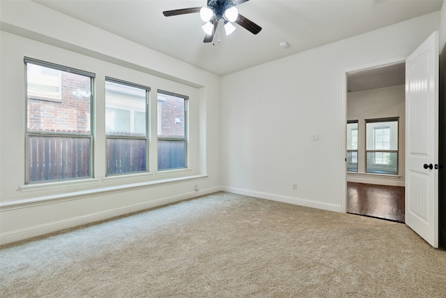 empty room featuring a healthy amount of sunlight, ceiling fan, and light carpet