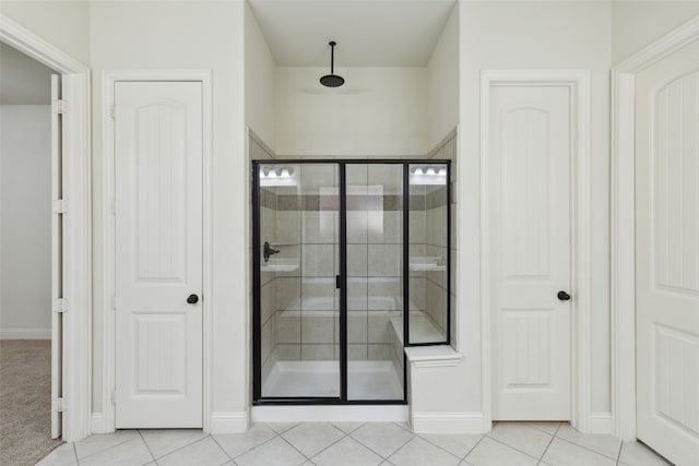 bathroom with a shower with door and tile patterned floors