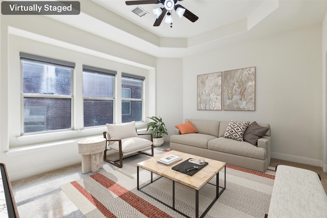 carpeted living room featuring ceiling fan and a raised ceiling