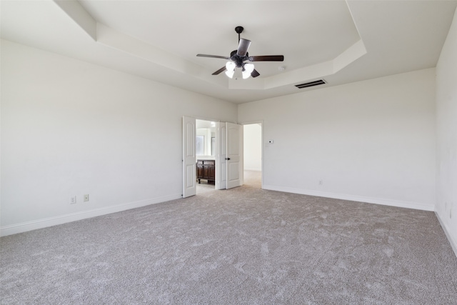 unfurnished bedroom featuring a tray ceiling, light carpet, and ceiling fan