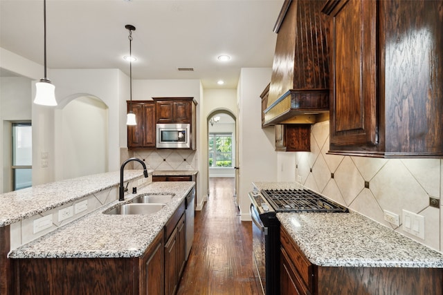 kitchen with custom range hood, hanging light fixtures, light stone countertops, stainless steel appliances, and dark hardwood / wood-style floors