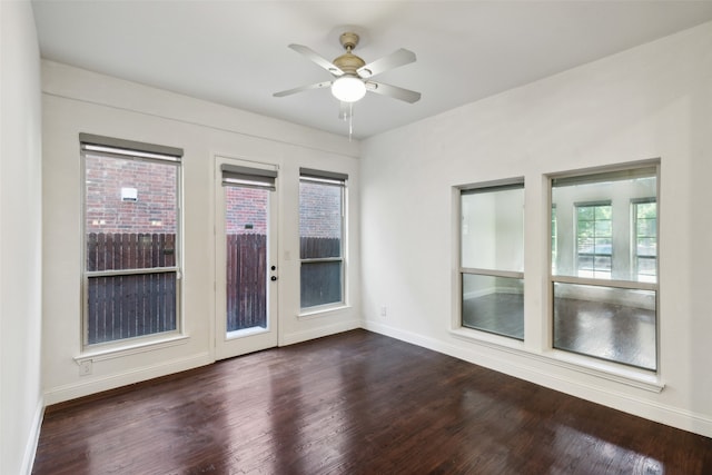 empty room featuring ceiling fan, dark wood-type flooring, and a wealth of natural light