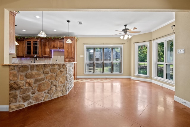 kitchen featuring light stone counters, kitchen peninsula, pendant lighting, ceiling fan, and ornamental molding